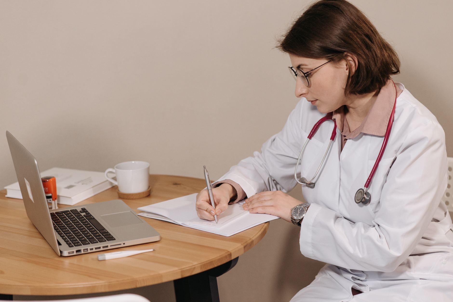 professionnelle de santé en blouse travaillant sur un ordinateur portable, prenant des notes