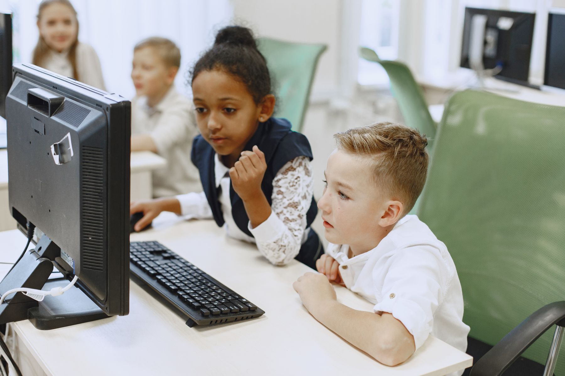 deux enfants concentrés devant un ordinateur en classe