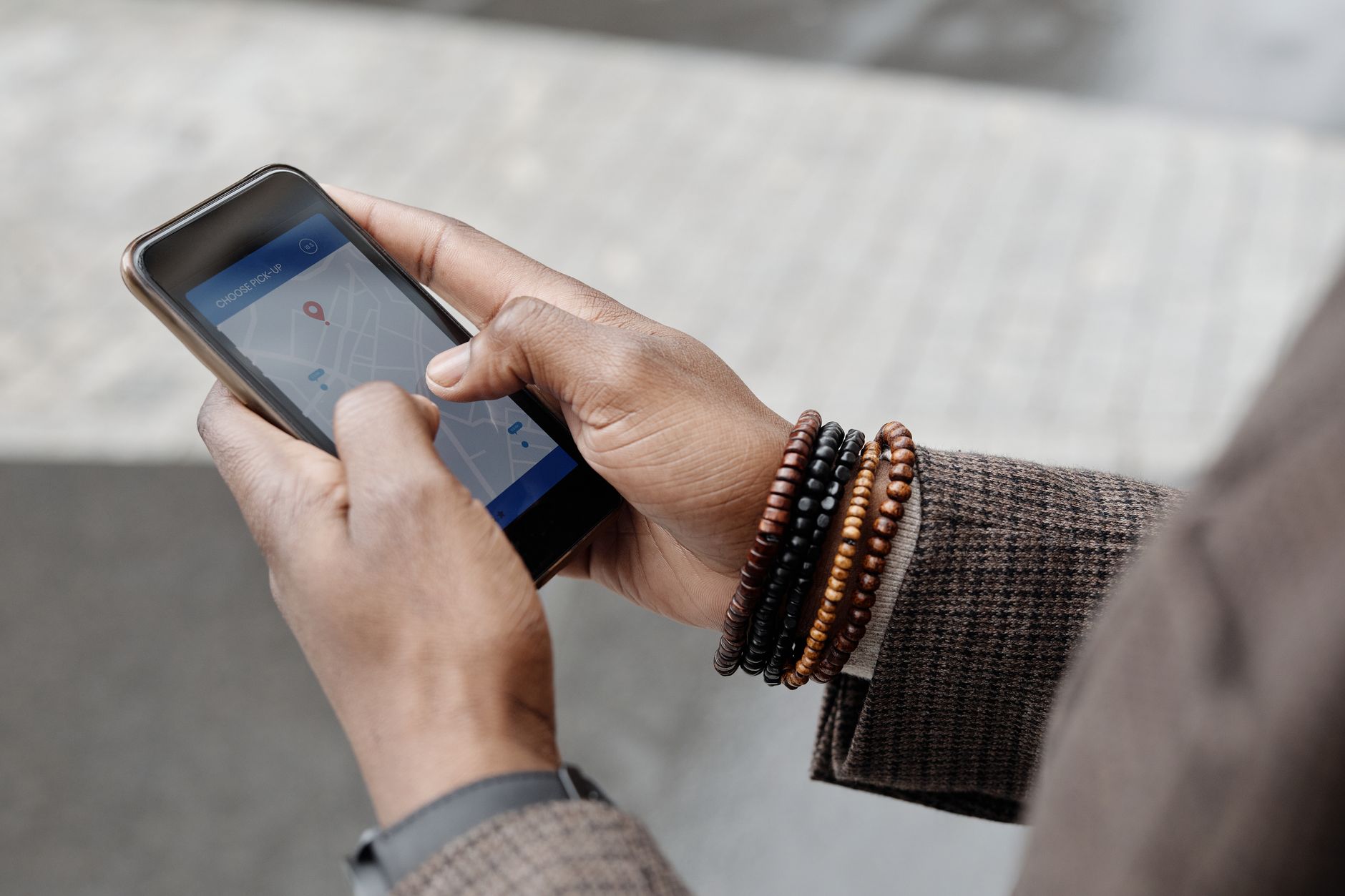 deux mains tenant un smartphone sur lequel une application de carte affiche un itinéraire