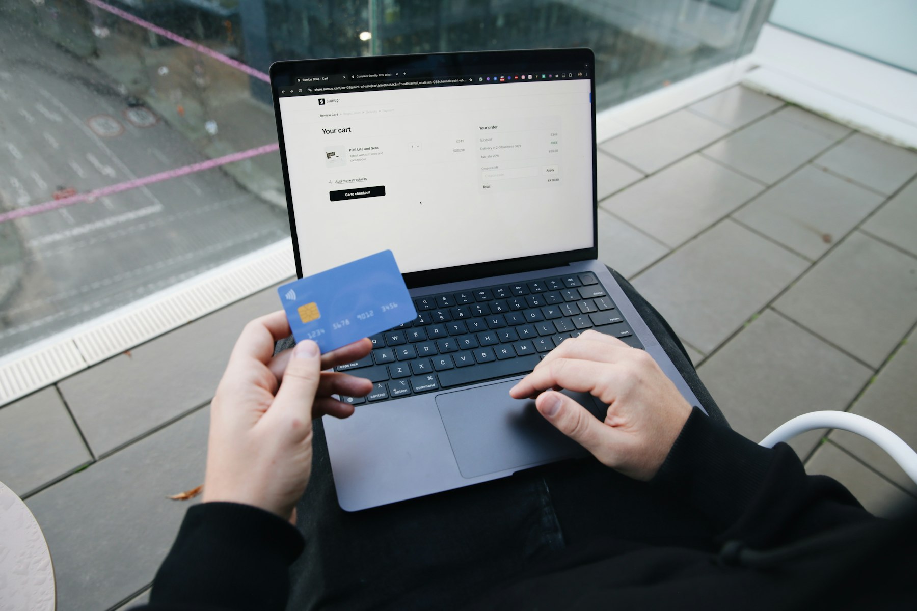 personne qui règle un achat en ligne avec une carte bancaire devant un panier affichant un champ code promo
