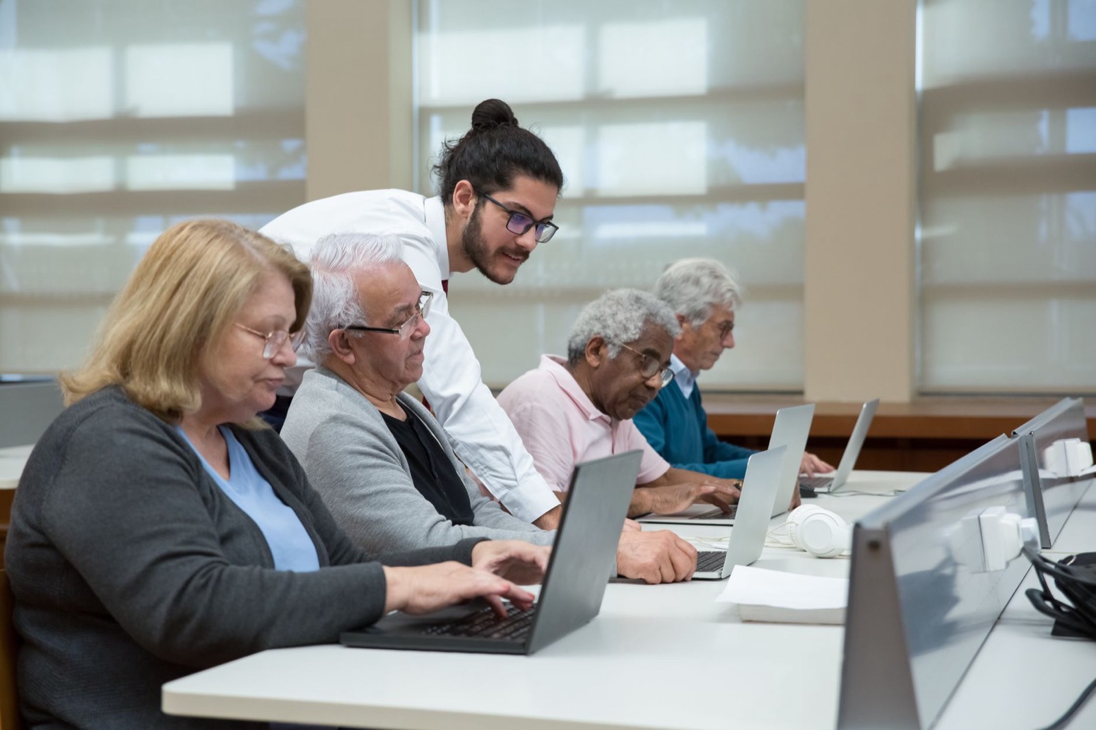 Formateur accompagnant une personne senior sur un ordinateur portable