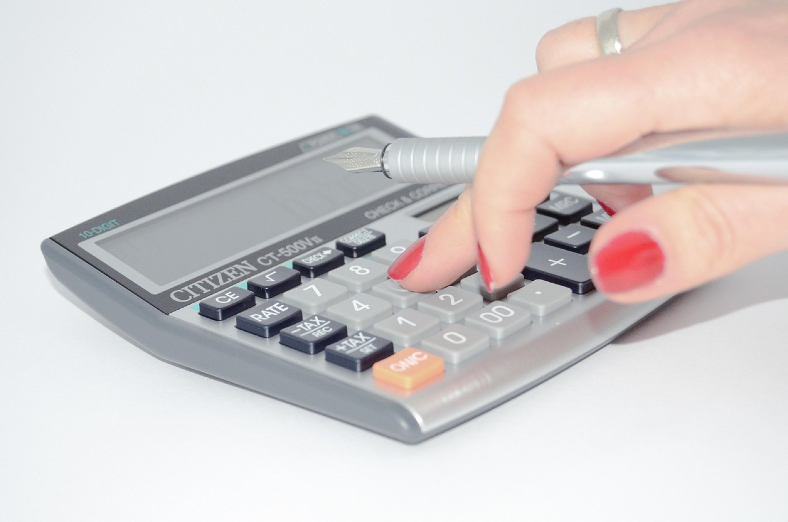Mains tenant une calculatrice et des documents de budget sur un bureau