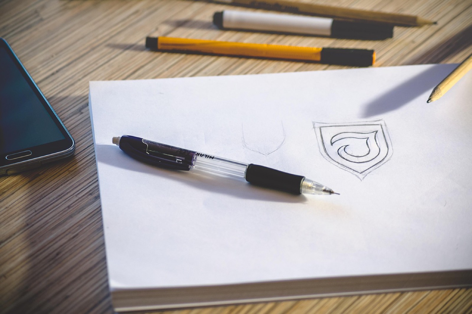 Croquis d'une page de site dessiné sur un carnet, posé à côté d'un clavier en bois