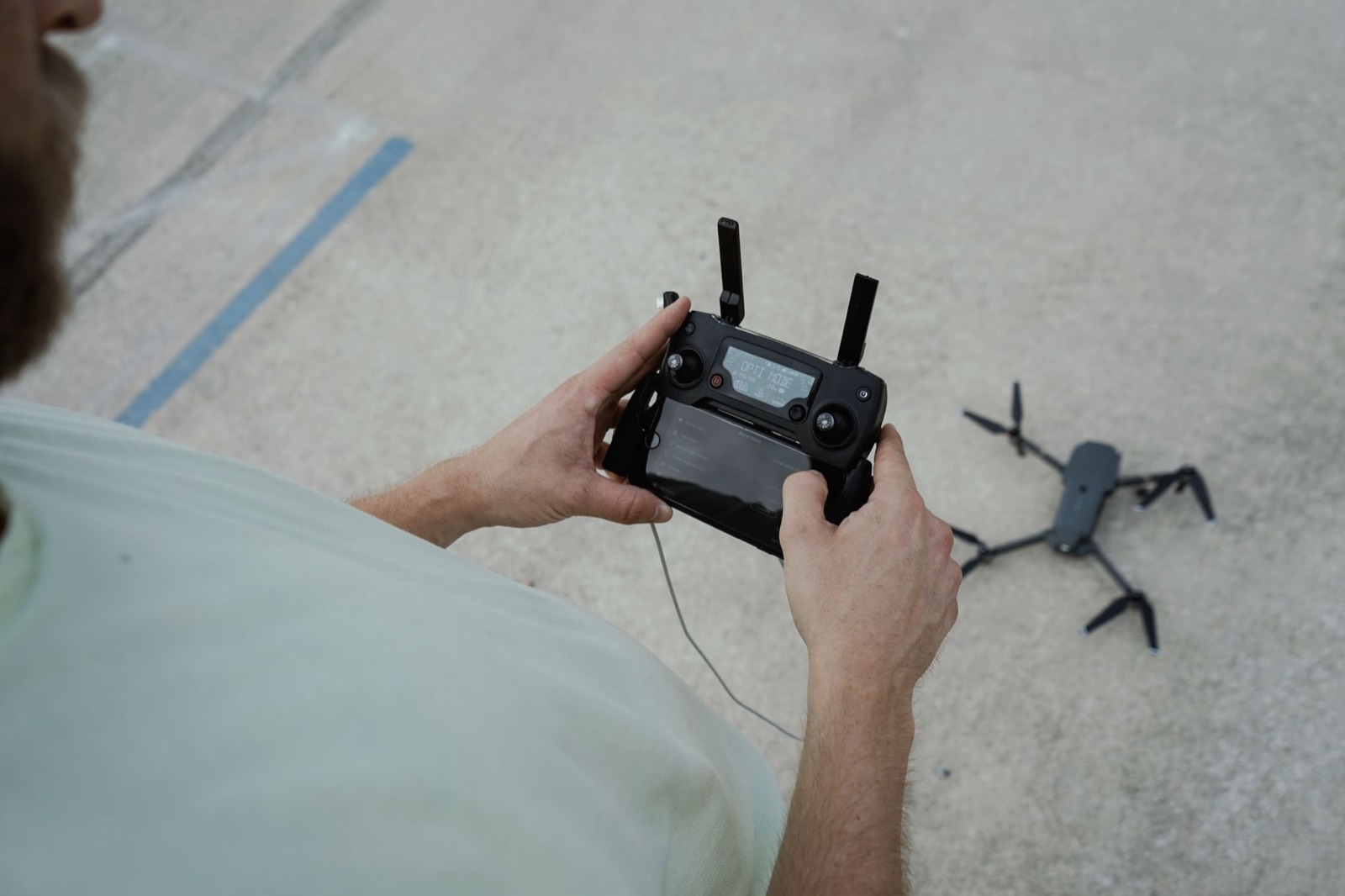 Pilote de drone professionnel réglant une télécommande en extérieur avant une prise de vue aérienne