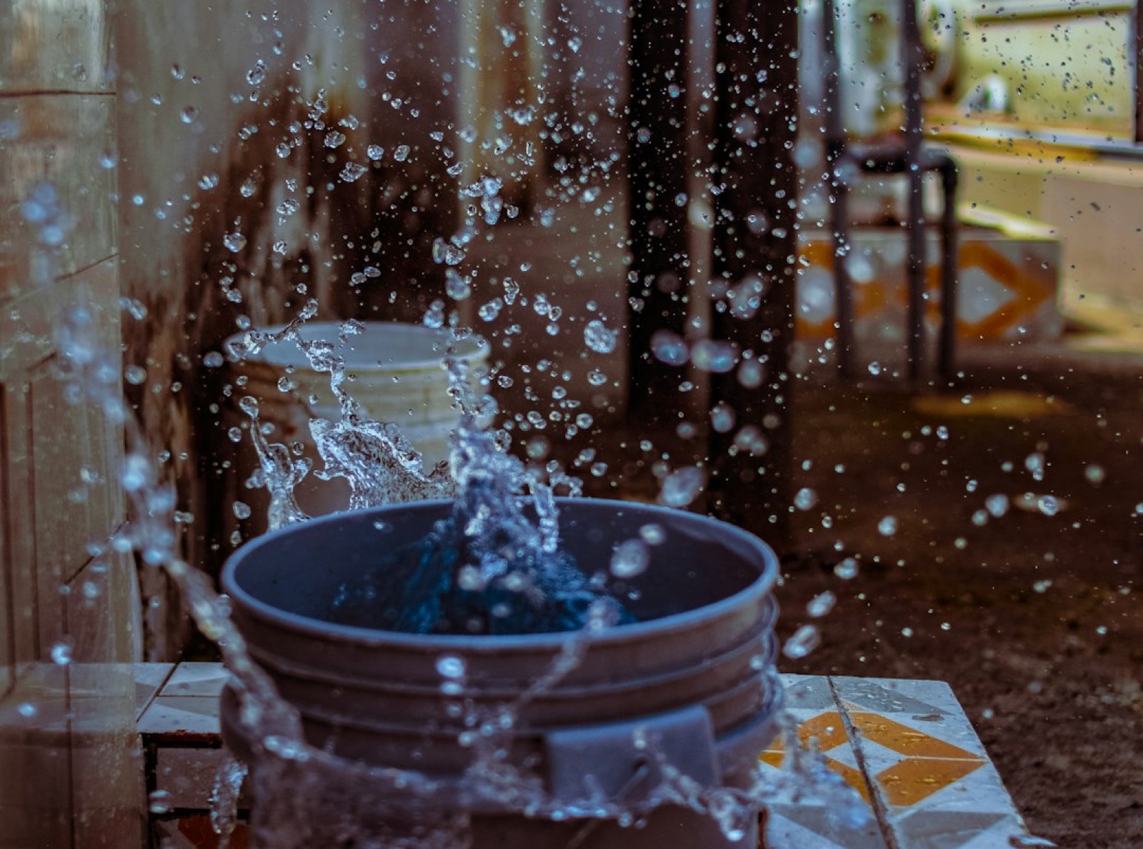 Tache d'eau au plafond et seau posé au sol pour recueillir une fuite de toiture