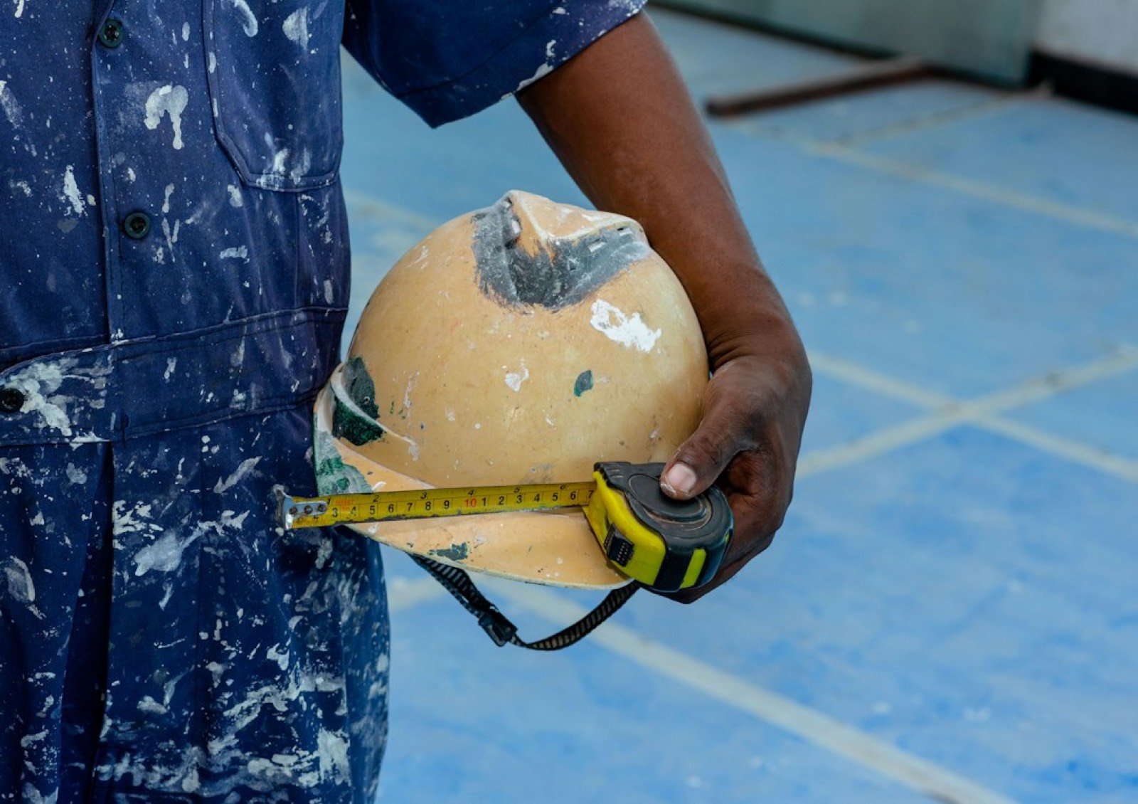 artisan qui mesure un mur avant travaux dans une maison d'hôtes