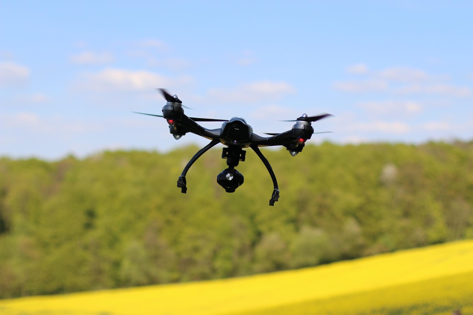 Télépilote tenant sa radiocommande sur un terrain dégagé avant le décollage d'un drone